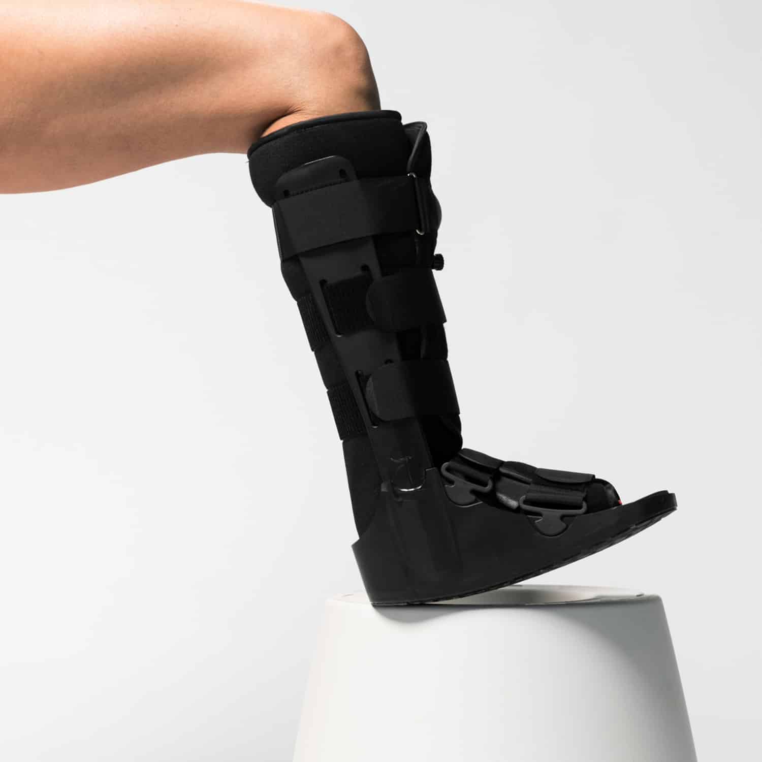 A woman wearing an AIRFLOWTM BOOT Tall on top of a stool.
