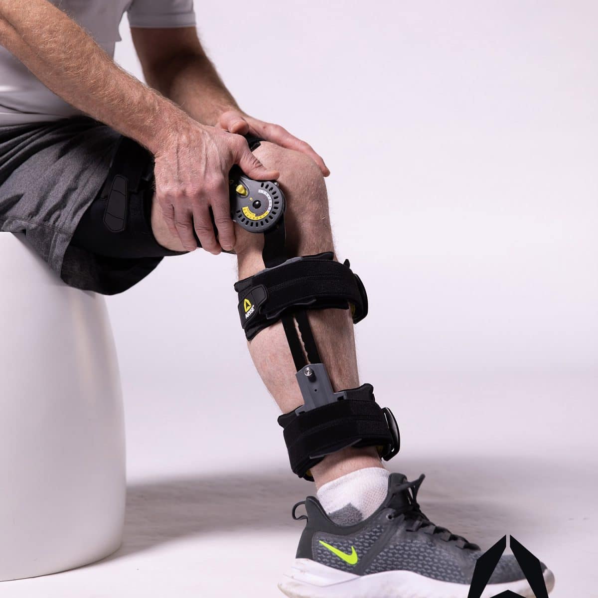 A man sitting on a stool with a TRU-RANGE+ POST-OP KNEE.