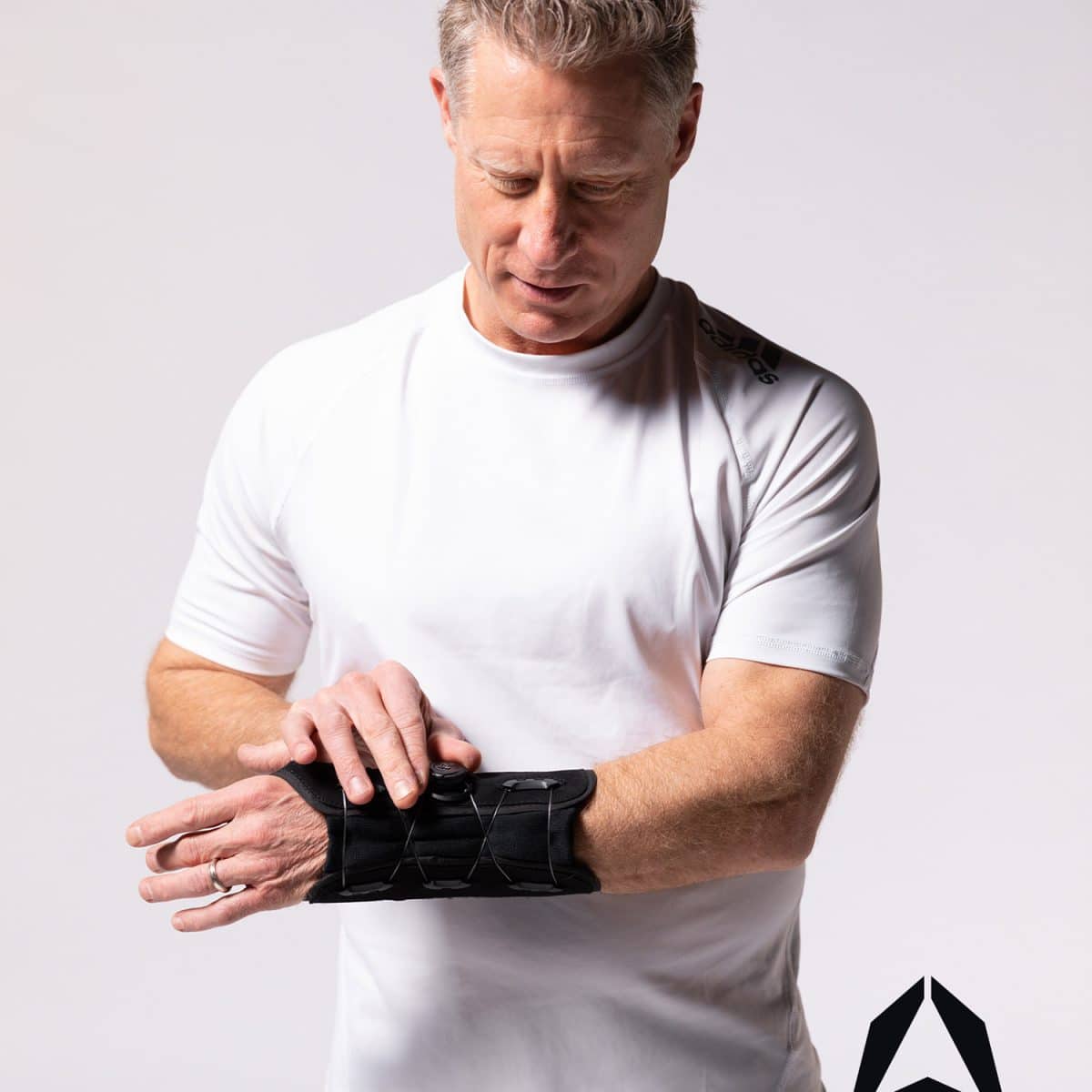 A man is putting on a PURESPEED+® WRIST brace from ARTIK Medical Supply.